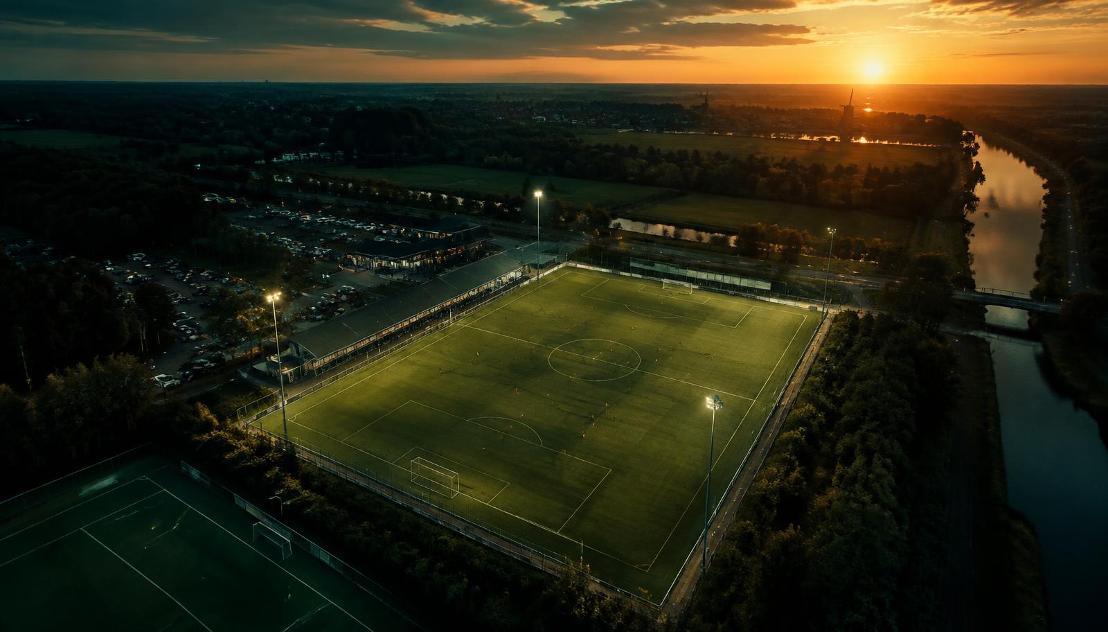 Cinematische drone-opname van een verlicht sportveld bij zonsondergang